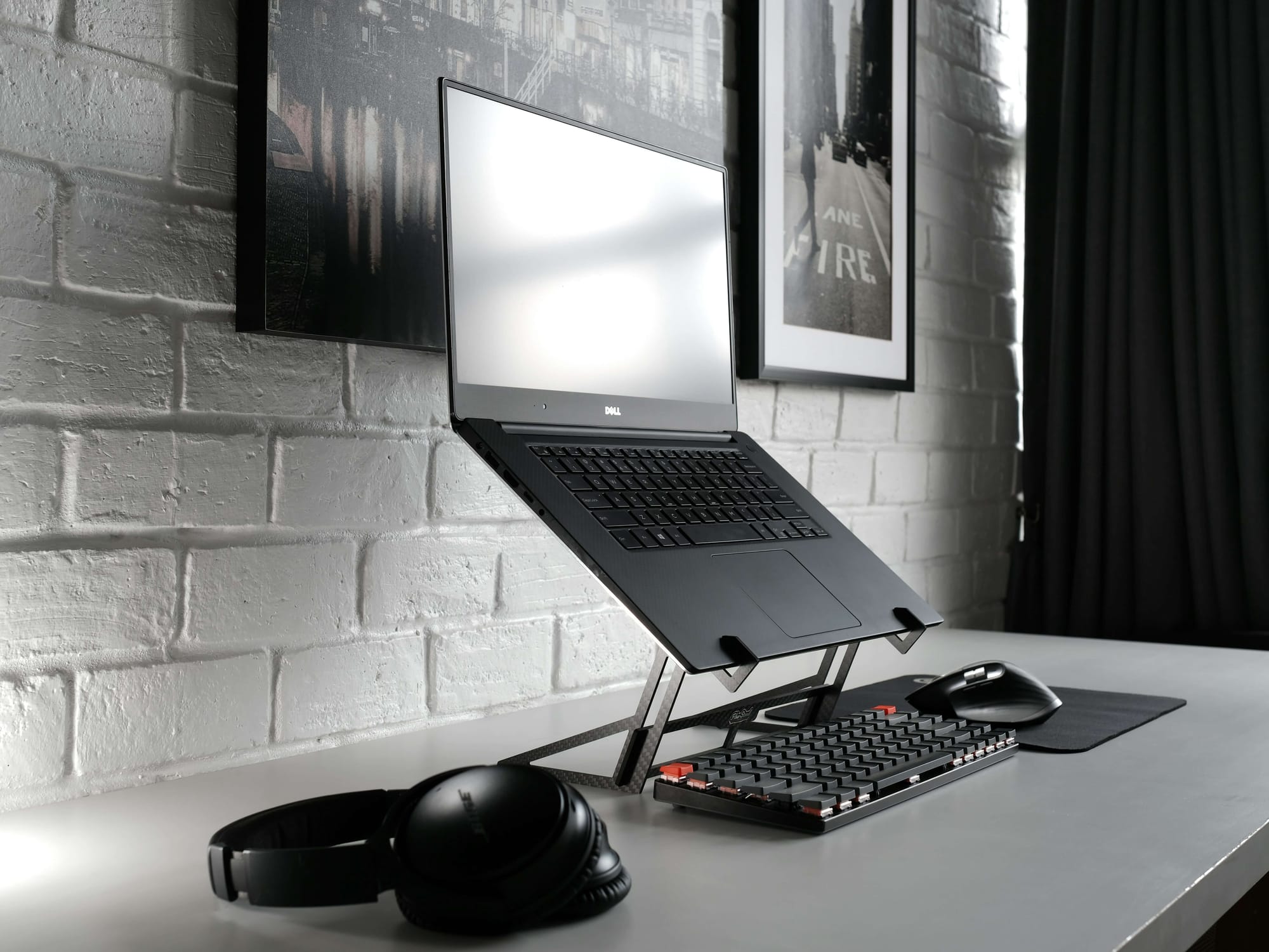 laptop and keyboard next to headphones behind white brick wall